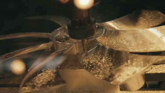 Milling machine works on the program and makes the impeller of brass. Sawdust fly around