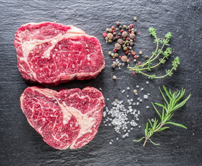 Rib eye steaks with spices on the black background.