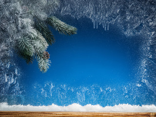 Frozen window and Christmas tree in snow against it.