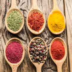 Assortment of colorful spices in the wooden spoons.