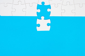 White, disassembled puzzle. On a blue background.Top view. Flat lay.