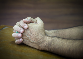 image of hands of a man praying to God on wooden background