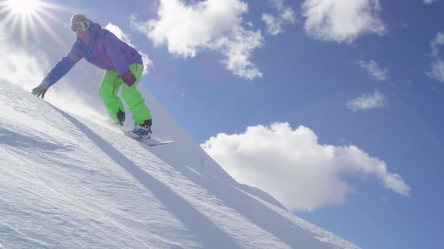 SLOW MOTION: Snowboarder riding powder snow and doing hand drag past the camera