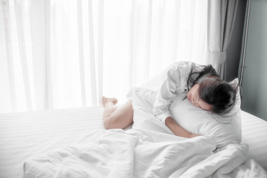 Cute girl on a soft white bed. She sleeping and relaxing.