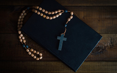 Fototapeta na wymiar Bible and a rosary with a cross. On a wooden background.Top view. Flat lay.