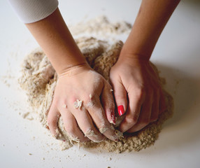 Woman's hands knead dough on a table