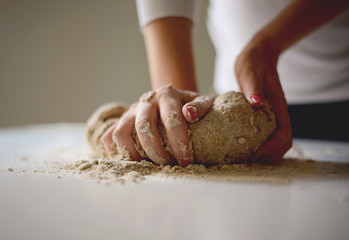 Woman's hands knead dough on a table