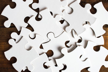 White puzzle in the bunch. On a wooden background.Top view. Flat lay.Macro. Close up.