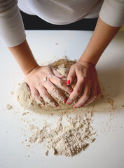 Woman's hands knead dough on a table