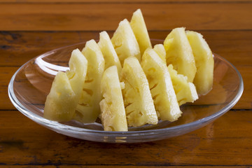 Pineapple slices on the plate on a wooden table.