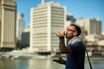 Enjoying city life. Handsome young man  having coffee to go. New York city in background