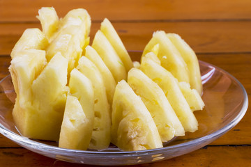 Pineapple slices on the plate on a wooden table.