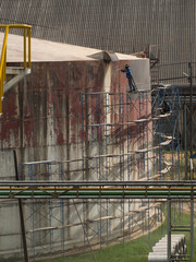 Worker cleaning storage tank by air pressure sand blasting.