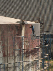 Worker cleaning storage tank by air pressure sand blasting.