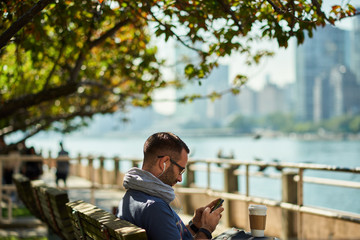 Enjoying city life. Handsome young man  having coffee to go. New York city in background