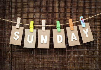 word Sunday design by white letterpress with box paper hang on rope by wooden peg over metal net...