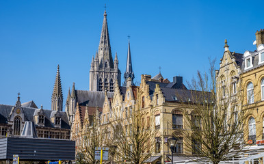 Fototapeta na wymiar Characteristic Flemish high pitch roof lines in the main square of Ypres (Ieper), Belgium, with the spire of St. Martin's Cathedral in the background