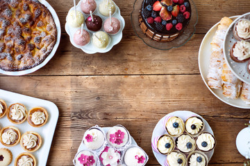 Table with cake, pie, cupcakes, tarts and cakepops. Copy space.