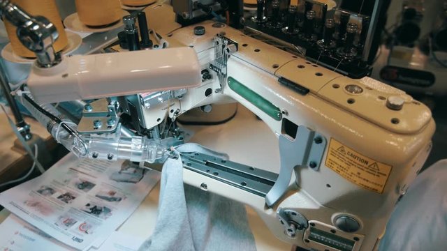 Workplace seamstress in a clothing factory - industrial sewing machine, spools of thread and fabric. Camera in motion