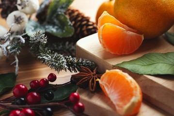 Top view of desktop with tangerines and leaves in Christmas decor.