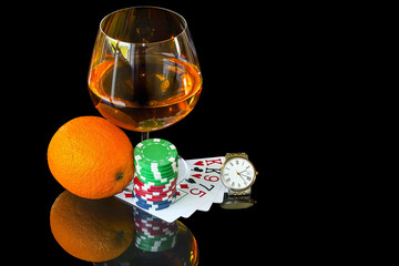 Playing cards with colorful chips and snifter with watch