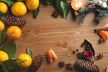 Top view of desktop with tangerines and leaves in Christmas decor.