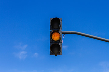 Traffic light with yellow light on and blue sky background