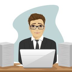young sad businessman working hard surrounded with paper documents and laptop