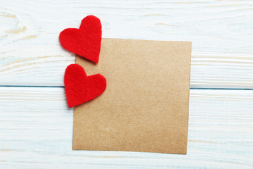 Red hearts and sheet of blank paper on a blue wooden table