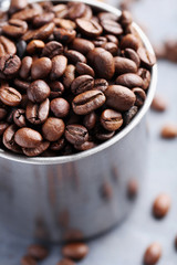 Roasted coffee beans in mug on grey table