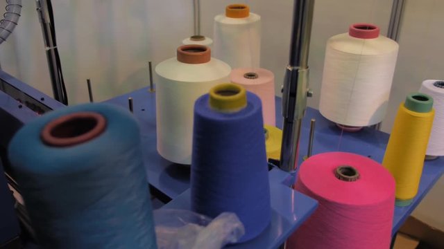 Rows spools of thread of different colors in the industrial loom . Different parts of the sewing machine. Loom for industrial manufacture of products in large scale. This machine produces socks