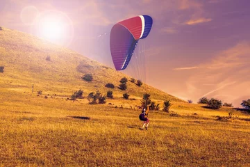 Acrylic prints Air sports   Paraglider over the green valley, sunset sky
