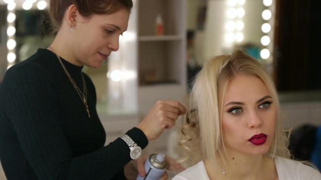 Hairdresser makes hairstyle blonde girl.