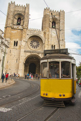 Naklejka na ściany i meble Lisbon street with the typical yellow tram and Lisbon Cathedral