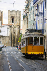 Lisbon street with the typical yellow tram and Lisbon Cathedral