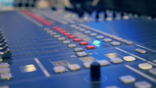 Professional video mixing console where many knobs and many reflections. Closeup. Dolly shot. Shallow depth of field