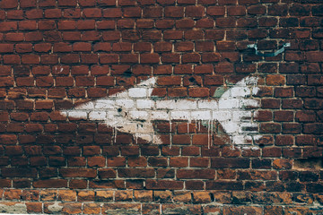 white arrow painted on red brick wall