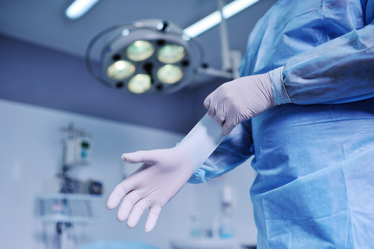 the surgeon puts on latex gloves  the background of the operating