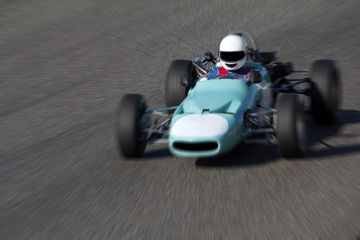 Vieille voiture de course roulant vite sur un circuit. 