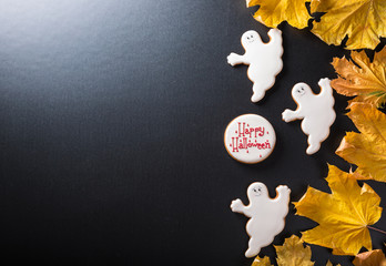 Funny delicious ginger biscuits for Halloween with yellow leaves on the dark background.