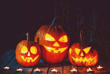 Halloween Pumpkins head jack lantern on the old boards in a spooky night landscape. Soft focus. shallow DOF