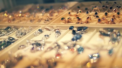 Beautiful jewelry on store shelves shimmer in different colors in rays of light. Closeup. Shallow depth of field