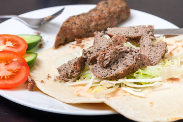 A minted lamb kofte kebab on a flatbread with salad