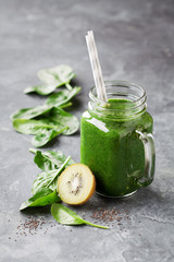 Healthy green smoothie with spinach, kiwi and chia seeds in a jar mug, selective focus