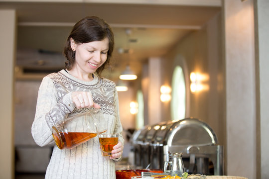 Woman Pouring a Drink at Breakfast
