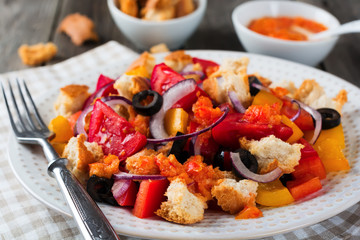 Salad with peppers, tomatoes, onions, olives and croutons with sousomna old wooden background. Selective focus.