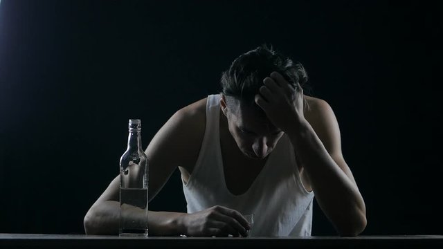 Depressed Man Drinking Vodka In A Dark Room. Man In Despair