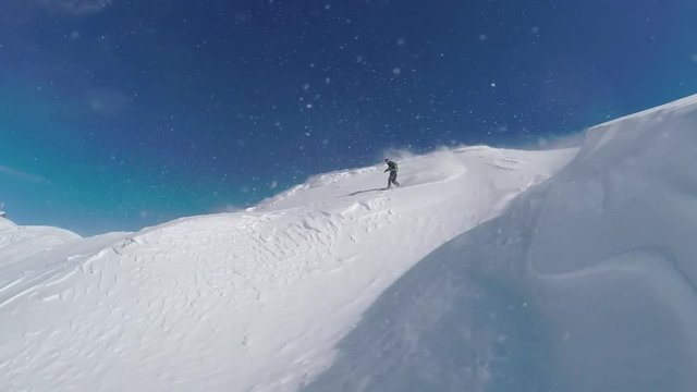 SLOW MOTION: Extreme freeride snowboarder doing powder turns in snowy mountains