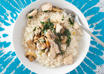 Overhead view of stir-fried chicken, mushrroms and spinach served with white rice