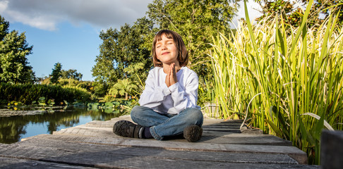 zen young yoga child meditating alone to breathe near water